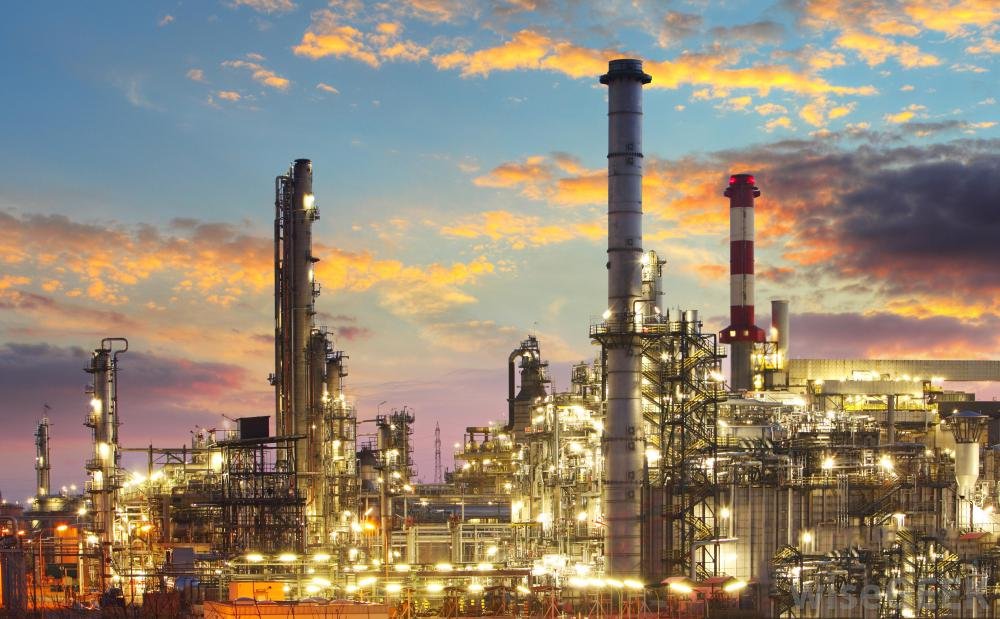 Refinery lit up at dusk under an orange and blue sky