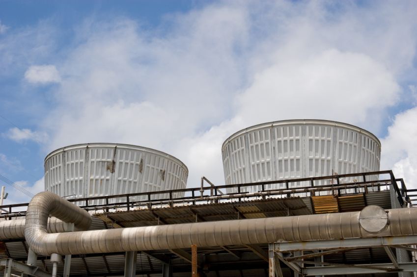 Industrial cooling tower fan stacks above process piping
